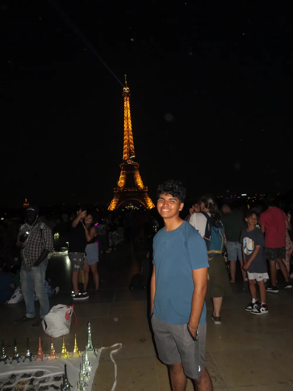 Maximus Fernandez standing near the illuminated Eiffel Tower at night