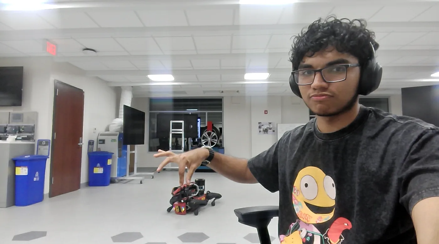 Maximus Fernandez beside a small robot in a University of South Carolina lab