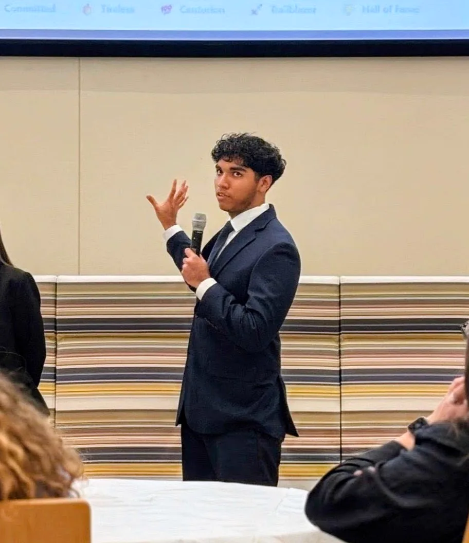 Maximus Fernandez presenting the SC Economics volunteer platform with a microphone
